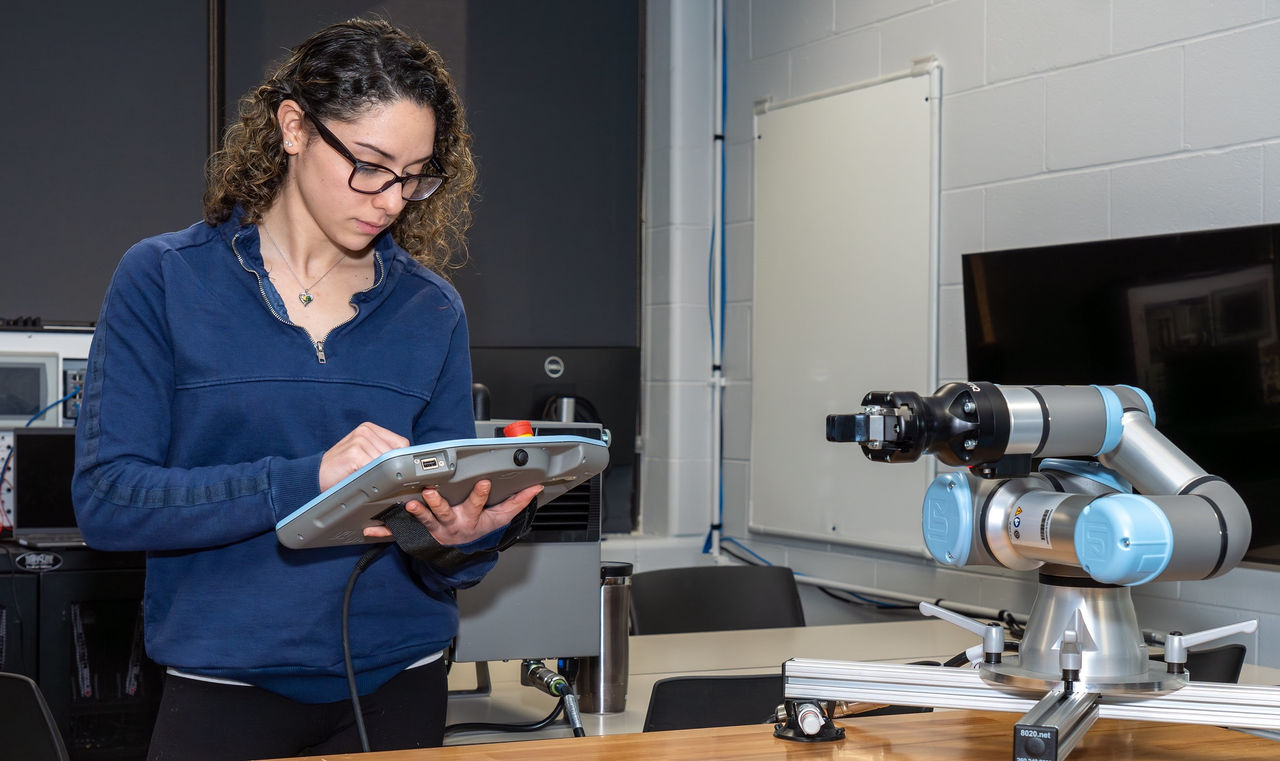 student using tablet next to robotic equipment