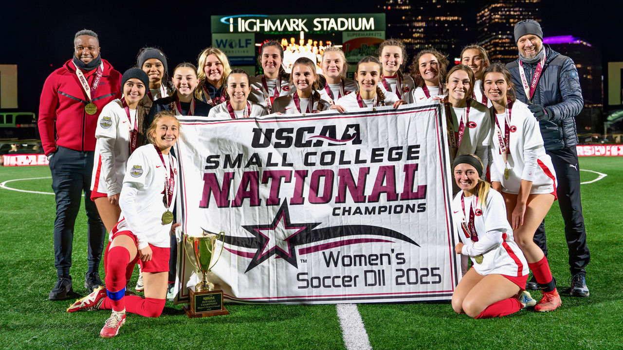 women's soccer team and coaches pose with championship banner for their third straight year