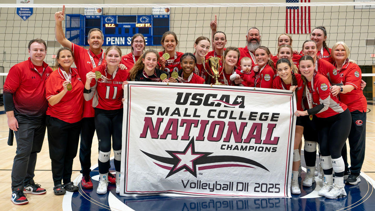 women's volleyball team and coaches pose with championship banner