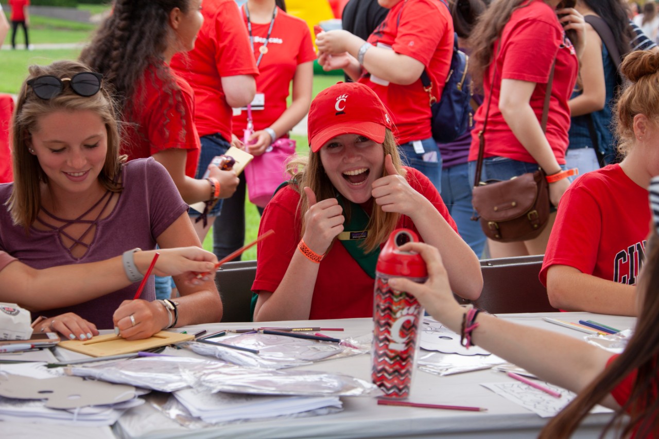 girl in UC shirt gives the camera a smile and thumbs up