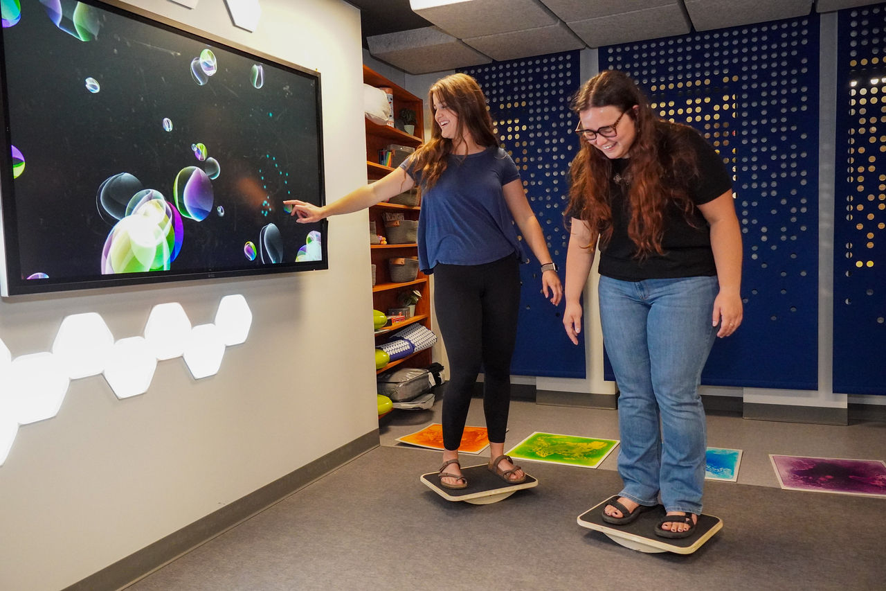 two students stand on balancing blocks in the sensory room