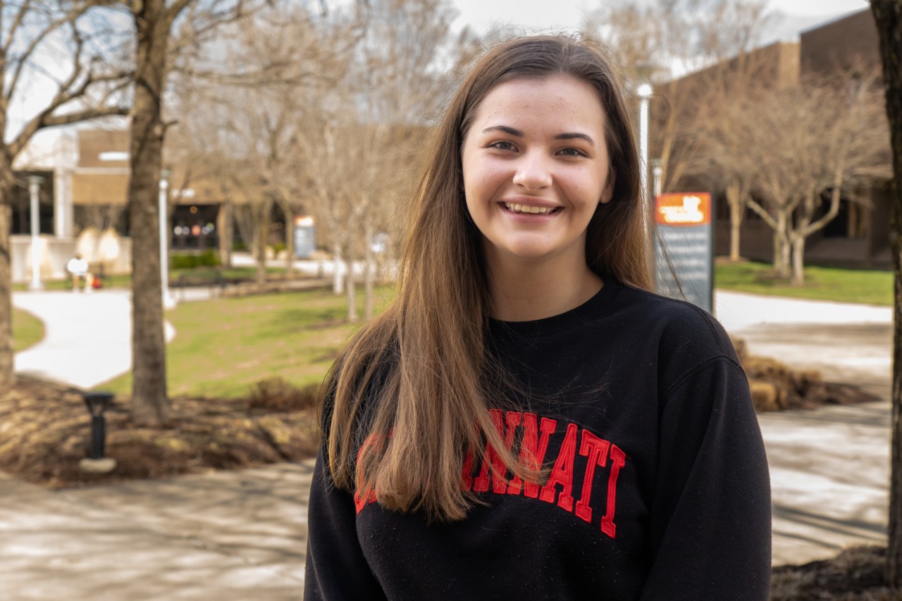 UC Clermont alumna Ayla Deck smiling on campus in UC shirt